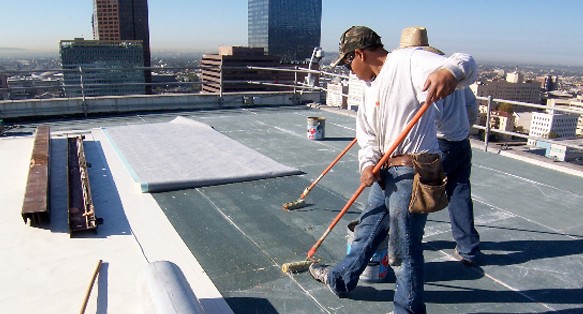 Workers applying coating to flat roof